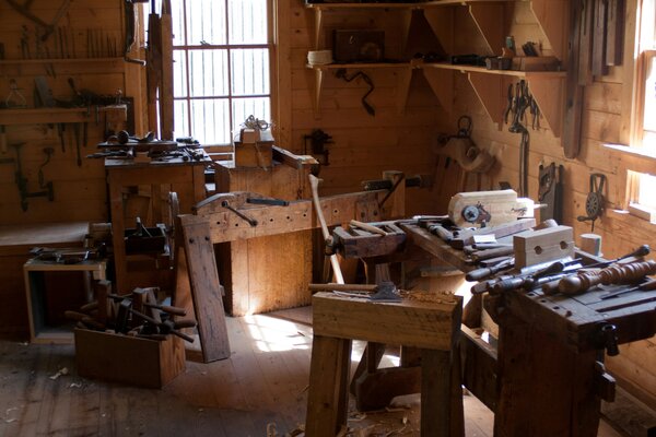 Eine rustikale Werkstatt mit Holzwerkbänken und traditionellen Werkzeugen, beleuchtet durch ein Fenster.